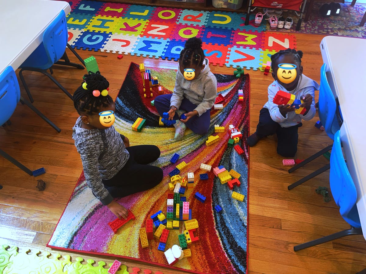 Three children playing with colorful building blocks on a rug