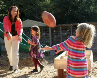 Adult and two children playing with a football outdoors