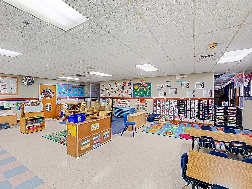 Empty colorful preschool or kindergarten classroom with tables and chairs