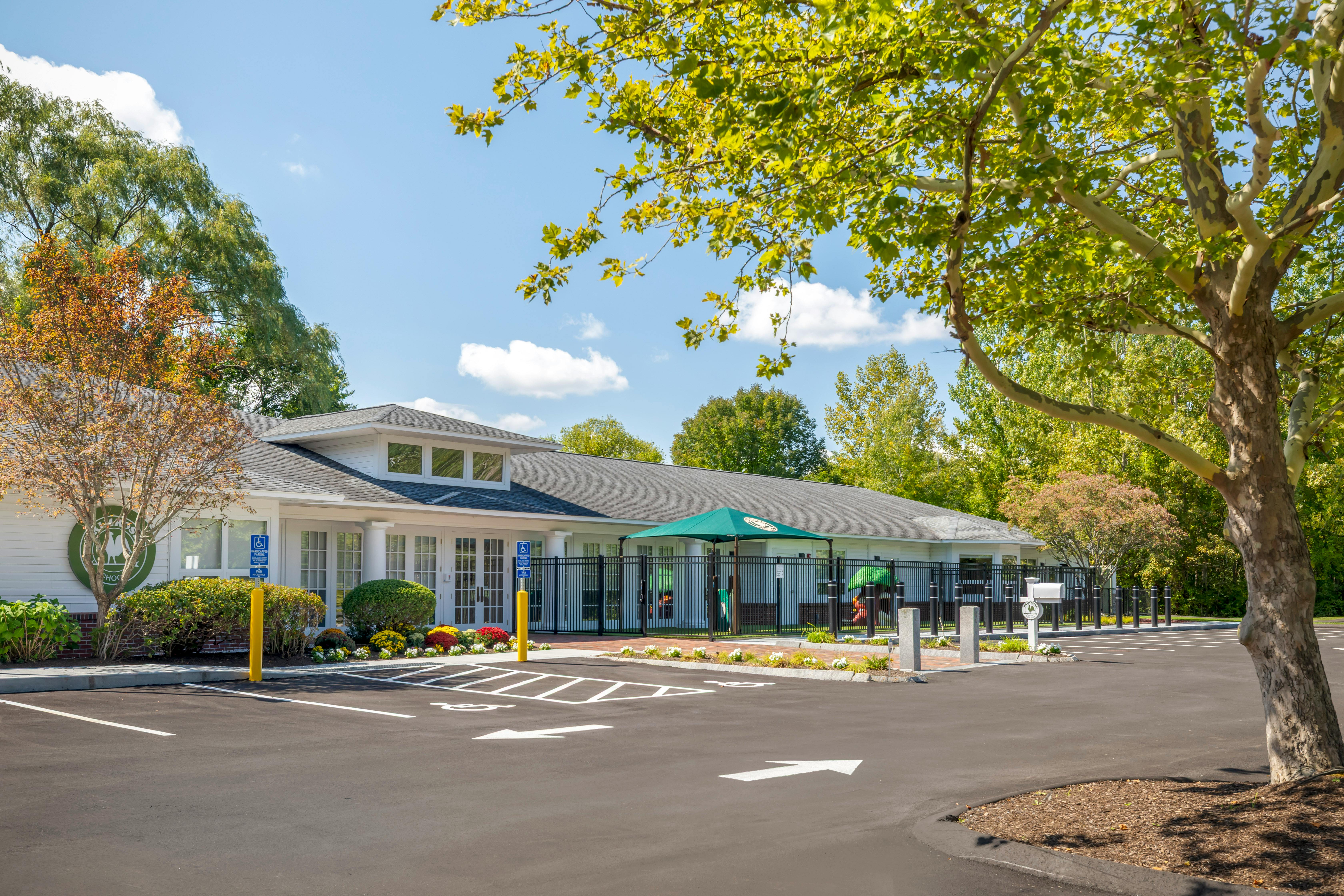 Exterior view of a building with a parking lot and fenced-in play area