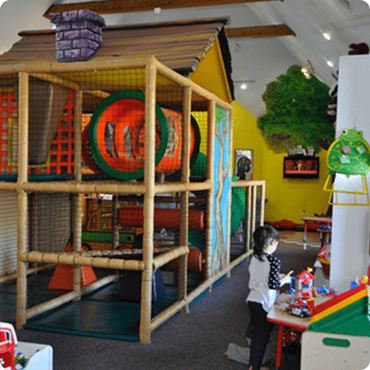 Child playing at a table next to an indoor playground structure