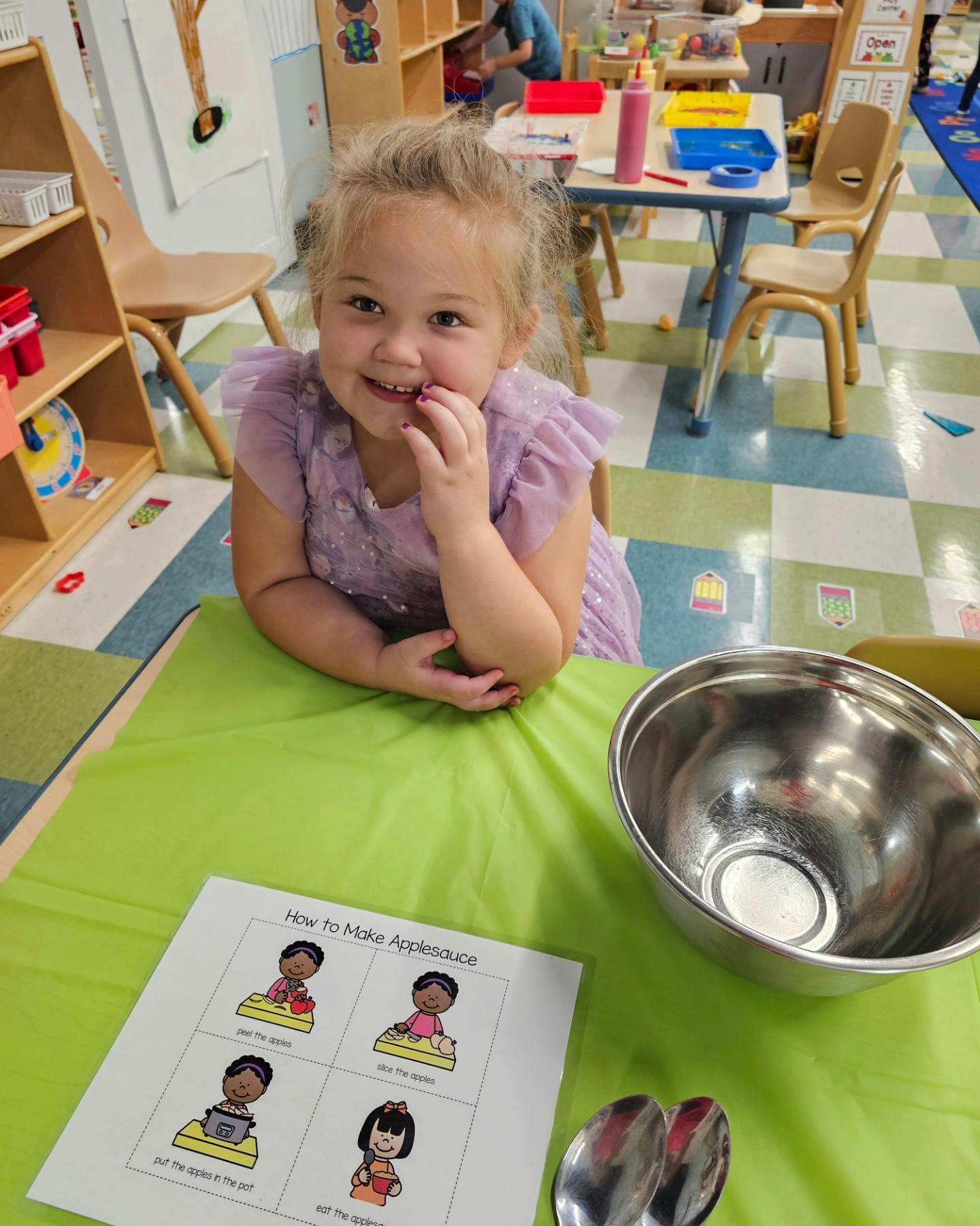 Child sitting at a table with a bowl and instructions in a classroom
