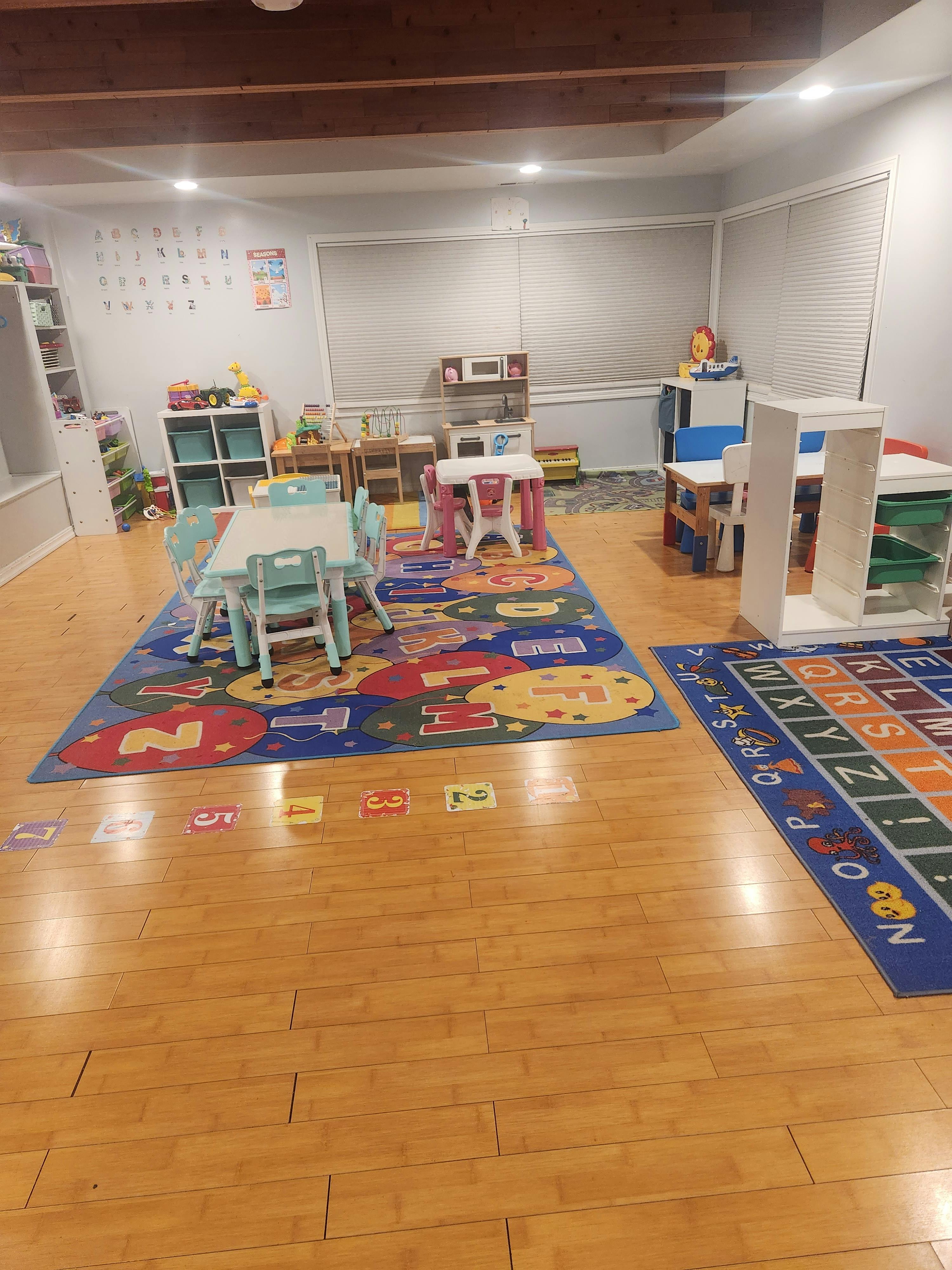 Playroom with small tables and chairs on colorful alphabet and number rugs