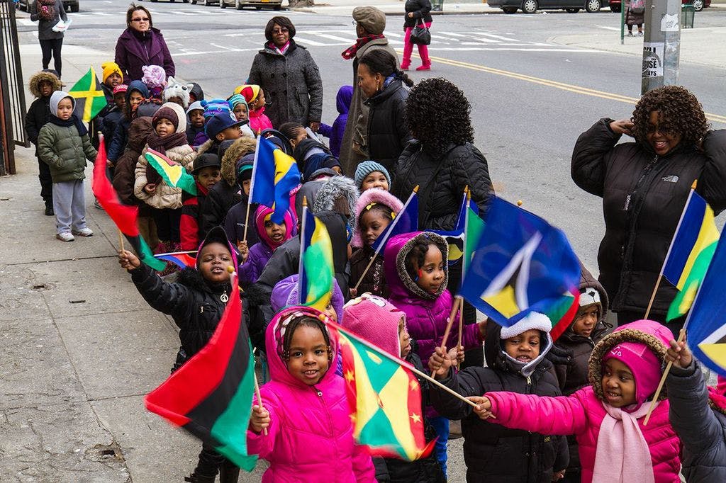 Children and adults holding flags on a sidewalk
