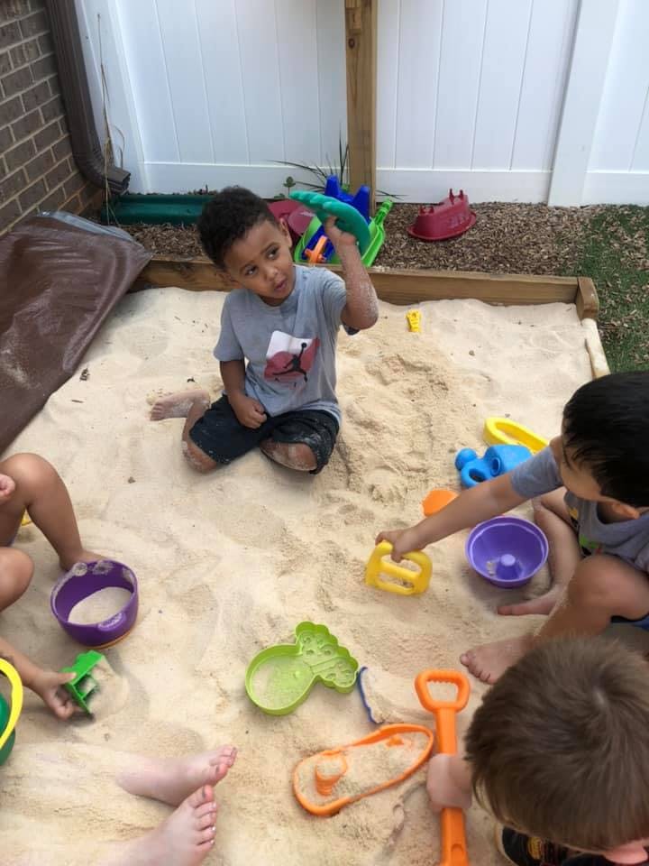 Children playing in a sandbox with toys