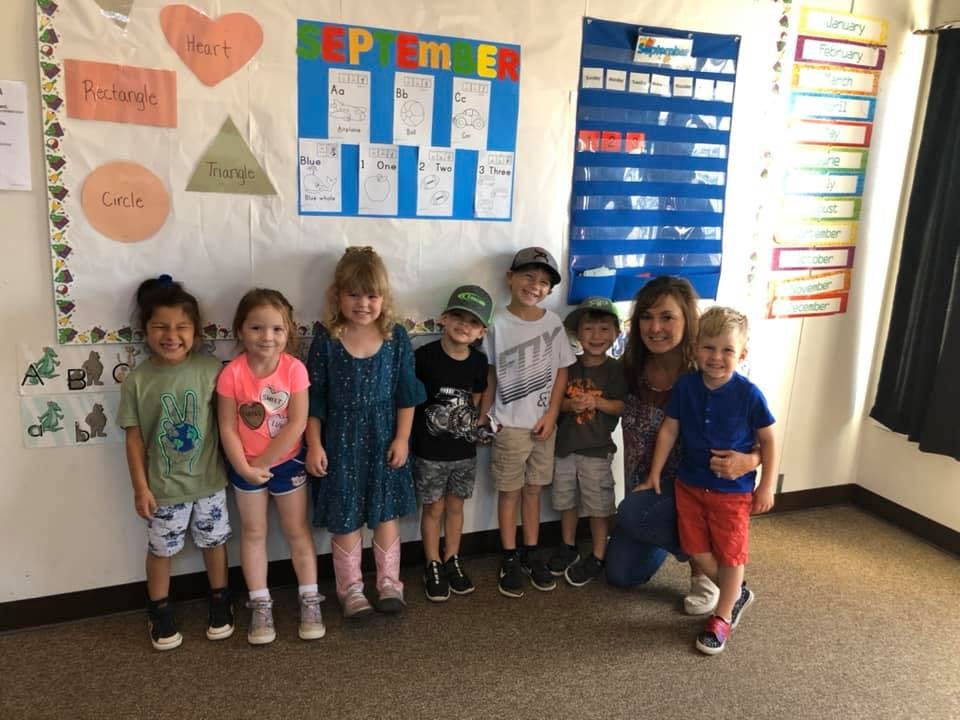 Adult and children posing in a classroom