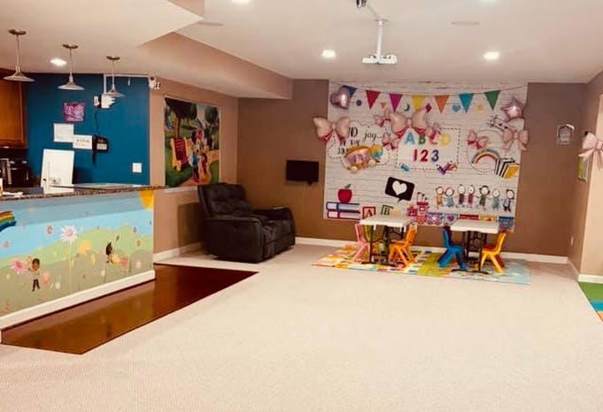 Children's play area with tables and chairs, a mural, and a lounge chair