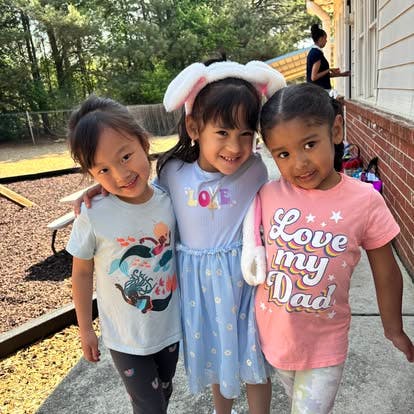 Three children standing together, one wearing bunny ears