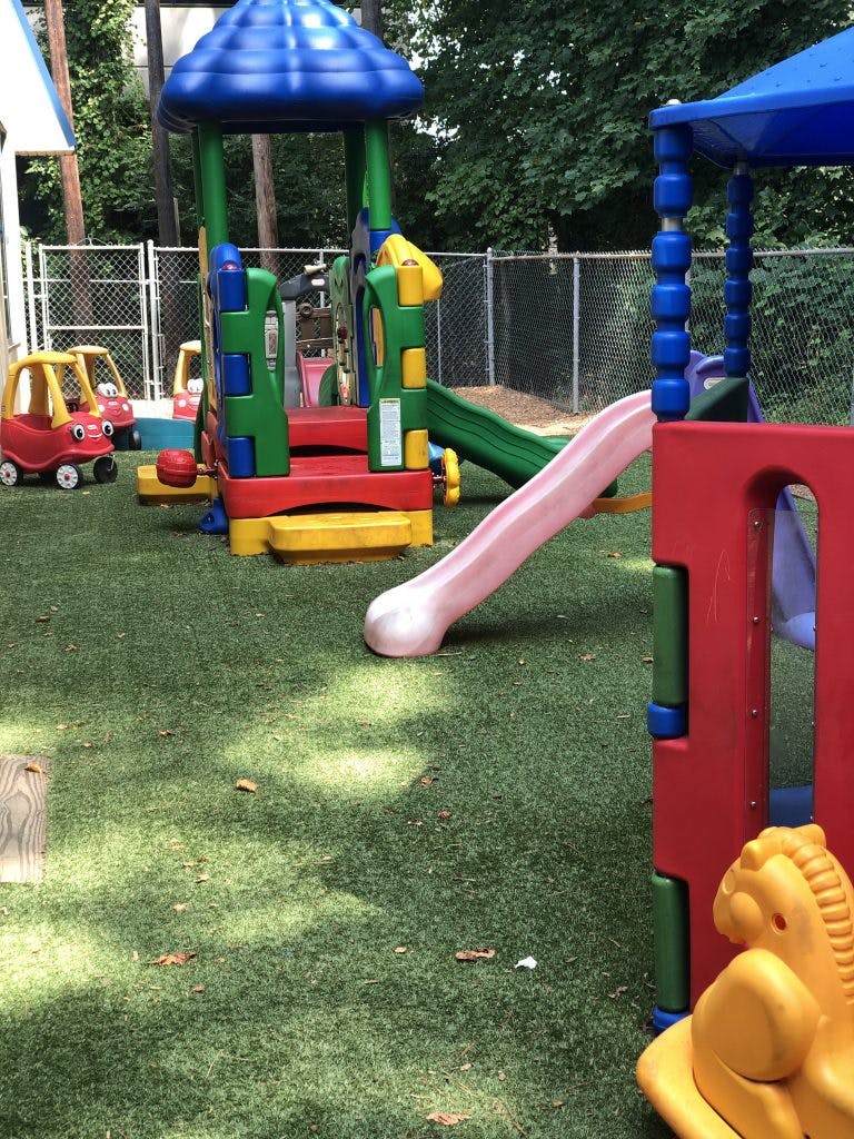 Playground with colorful slides and ride-on toys on artificial turf