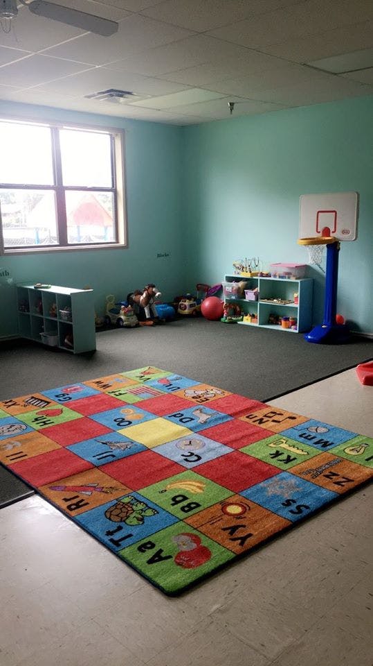 Playroom with an alphabet rug, toys, and a small basketball hoop