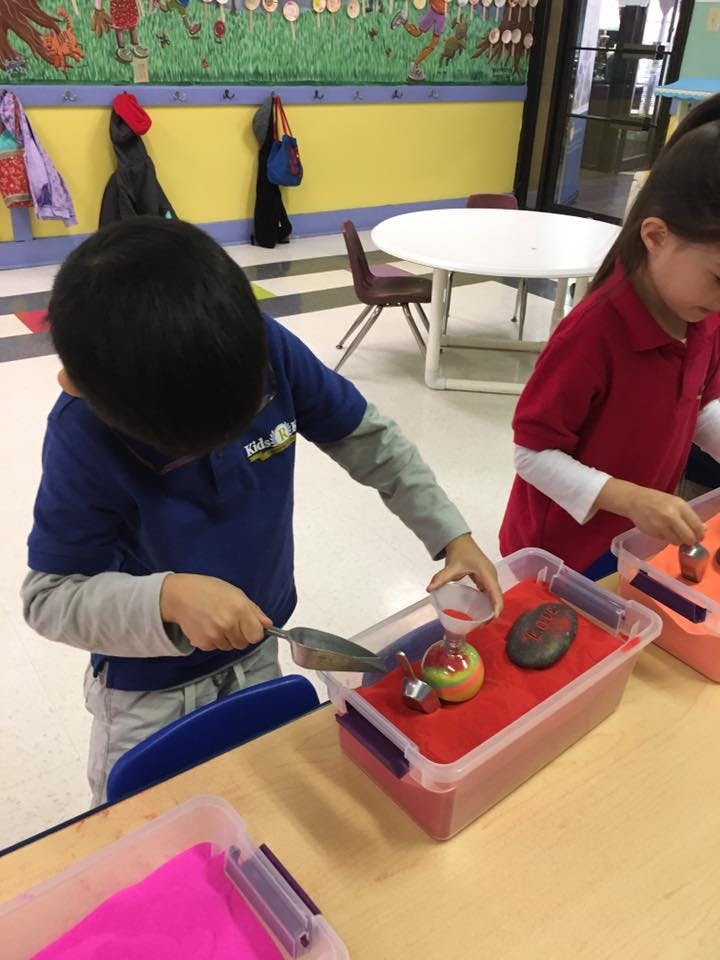 Child playing with sand and toys in a classroom