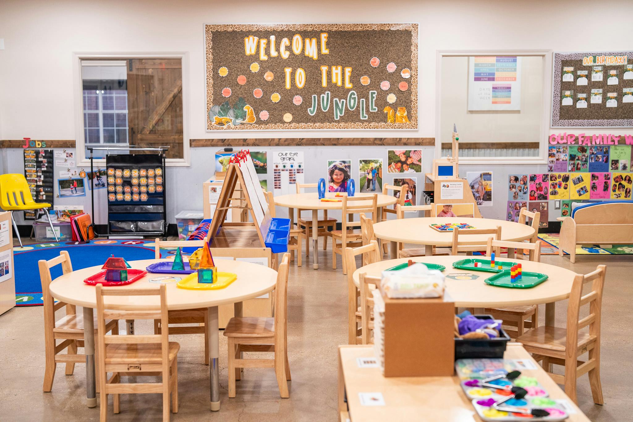 Round tables and chairs in a classroom with educational displays on the walls
