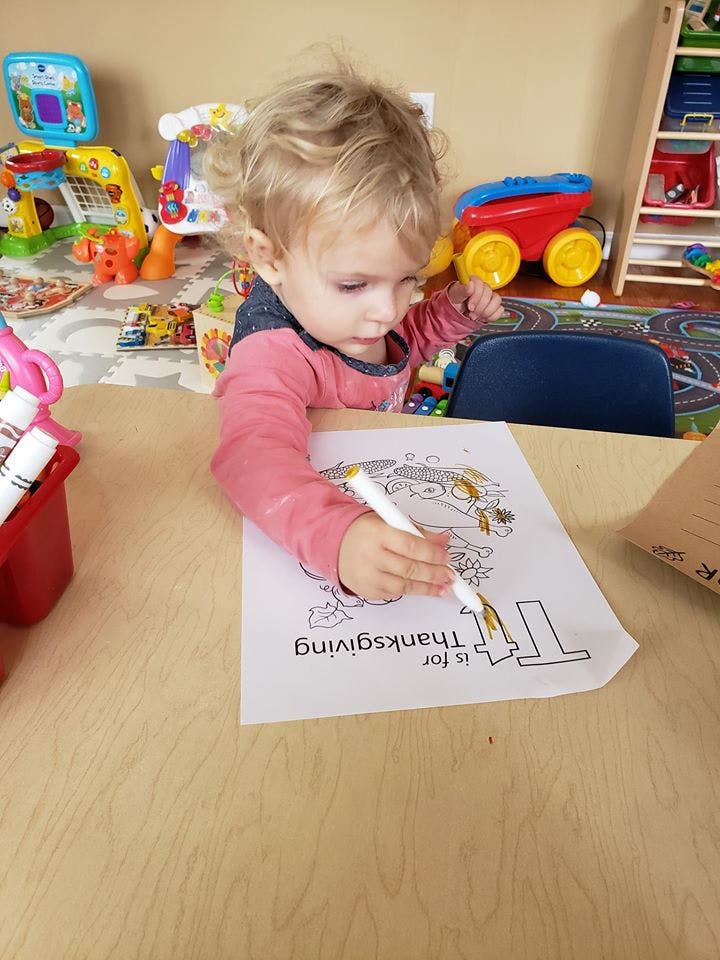 Child coloring a Thanksgiving themed picture at a table