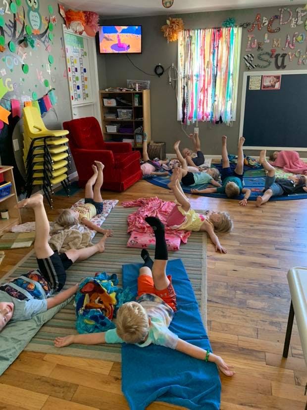 Children lying on mats with their legs raised in a classroom