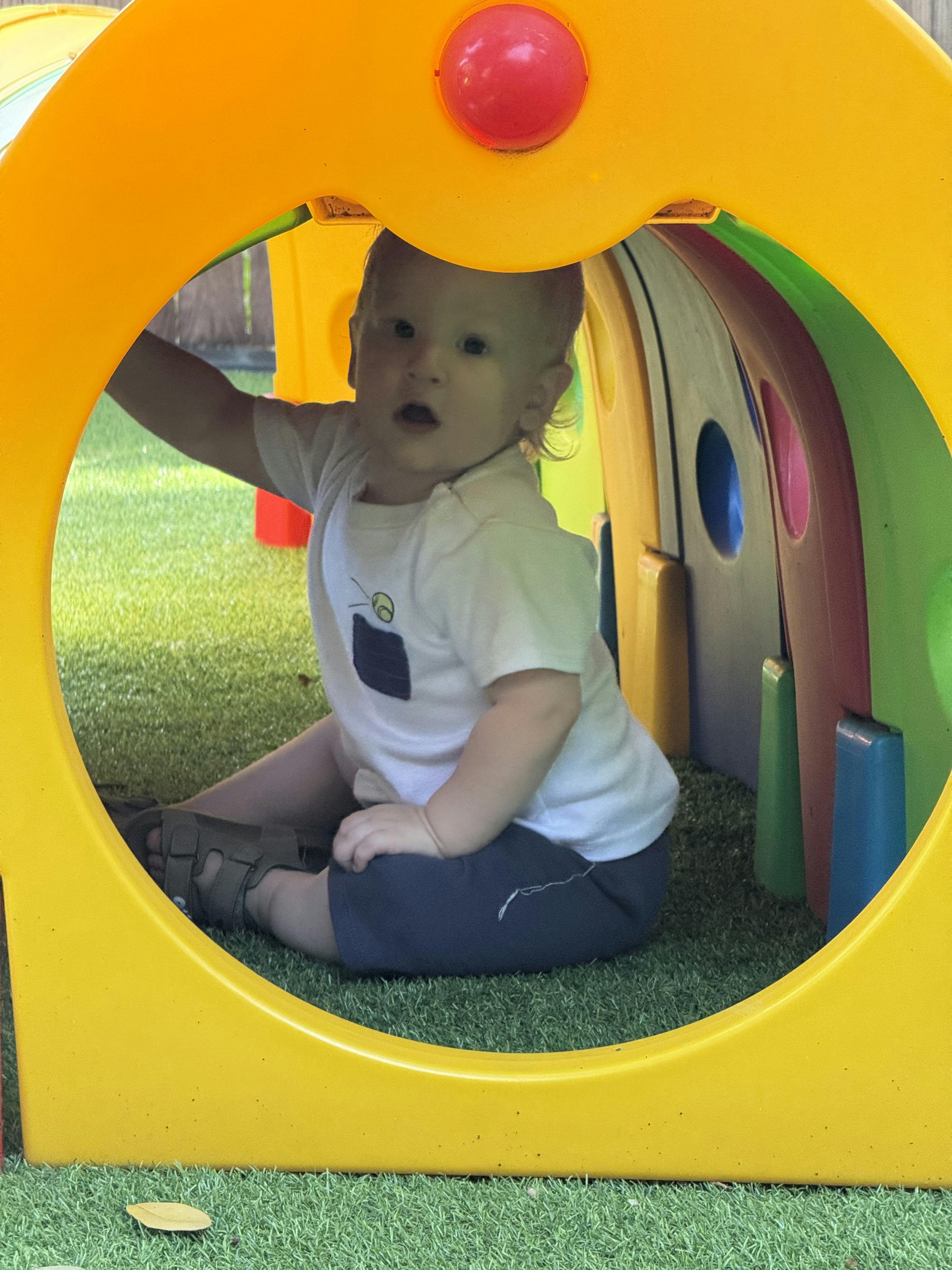 Child sitting inside a colorful plastic play tunnel