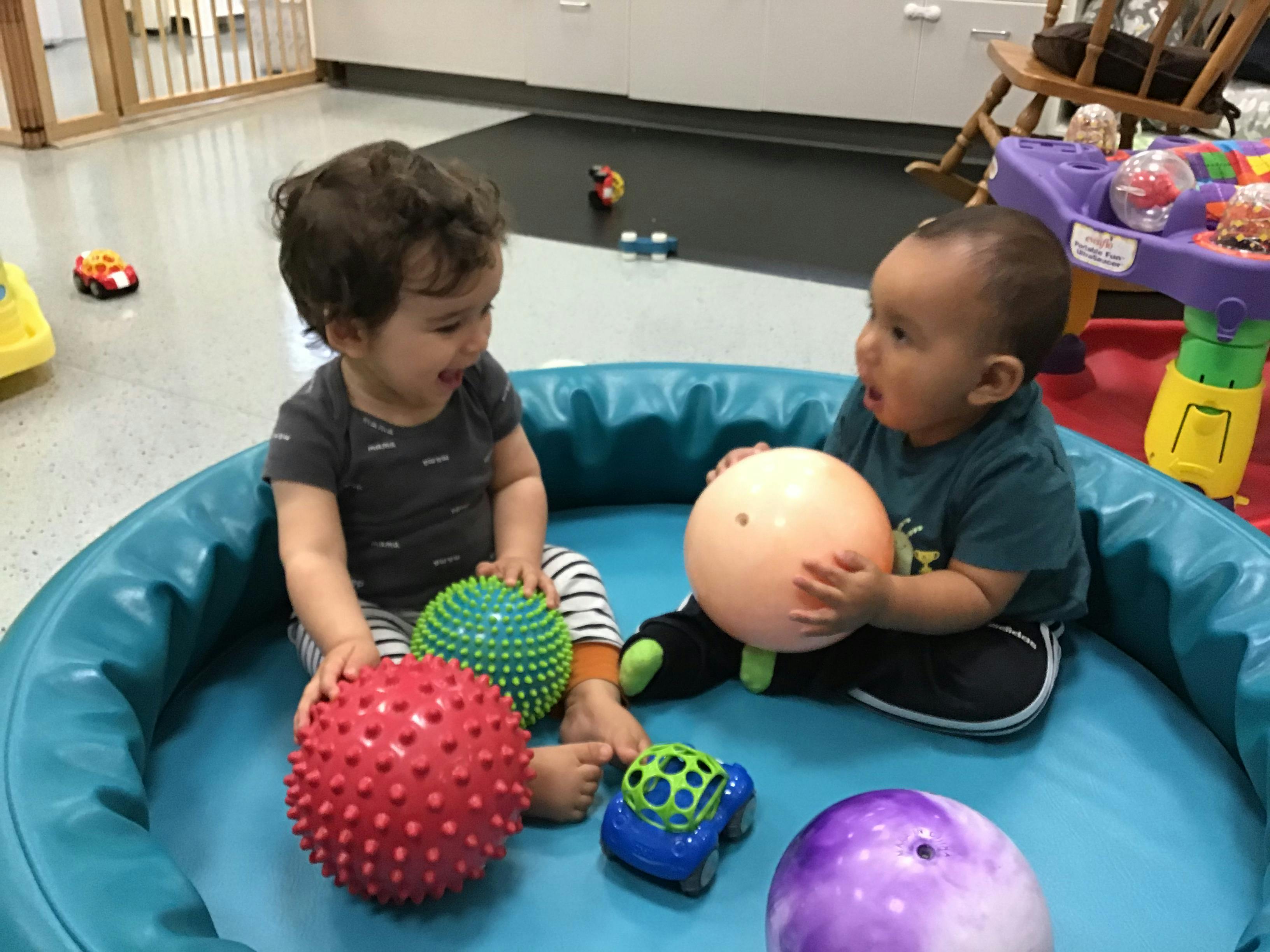Two children playing with balls in a soft play area