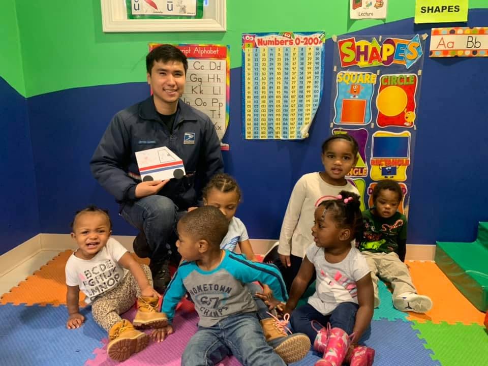 Adult holding a paper truck with children sitting around them
