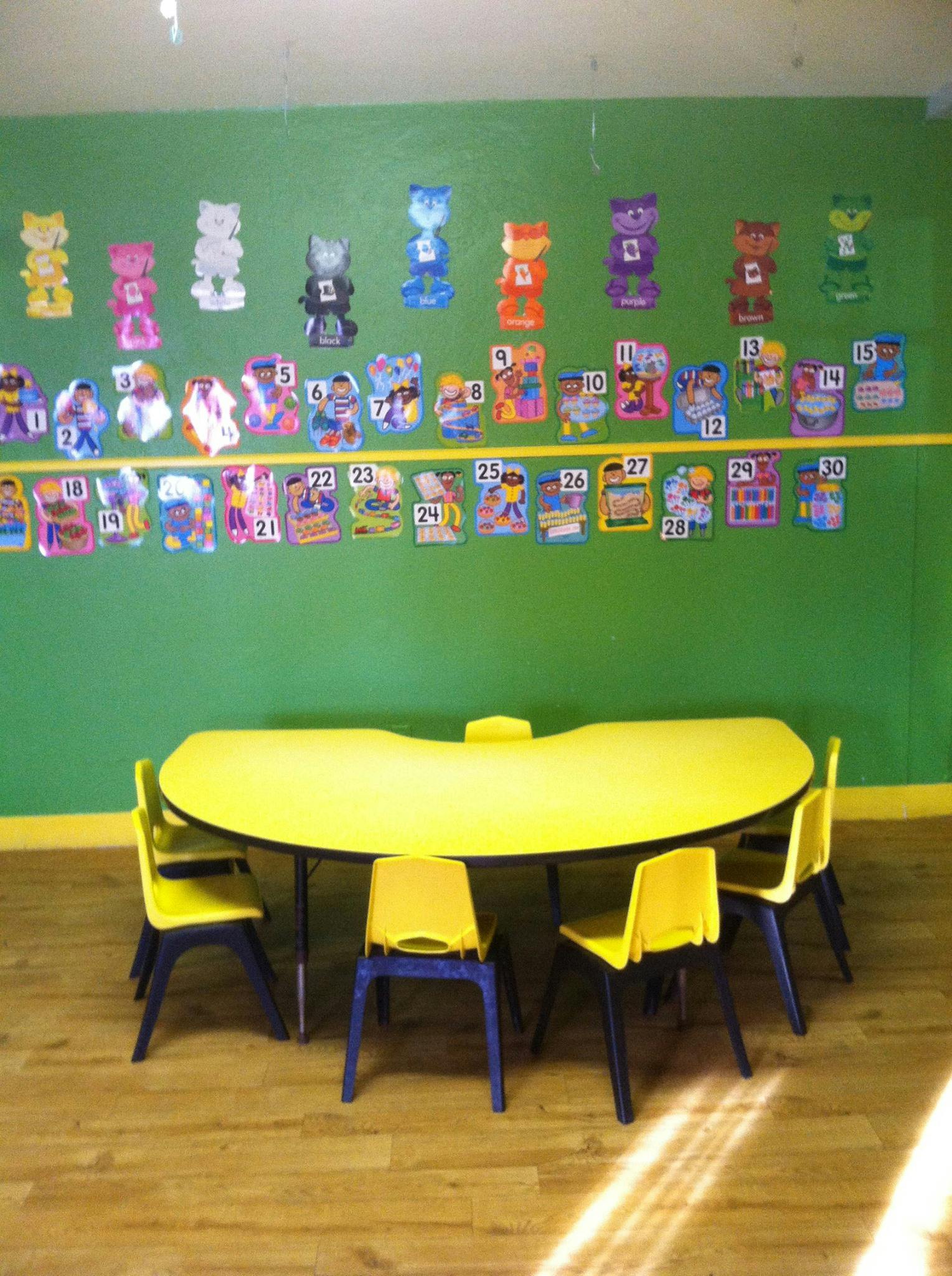 Classroom with a yellow table and chairs, and colorful cutouts on the wall