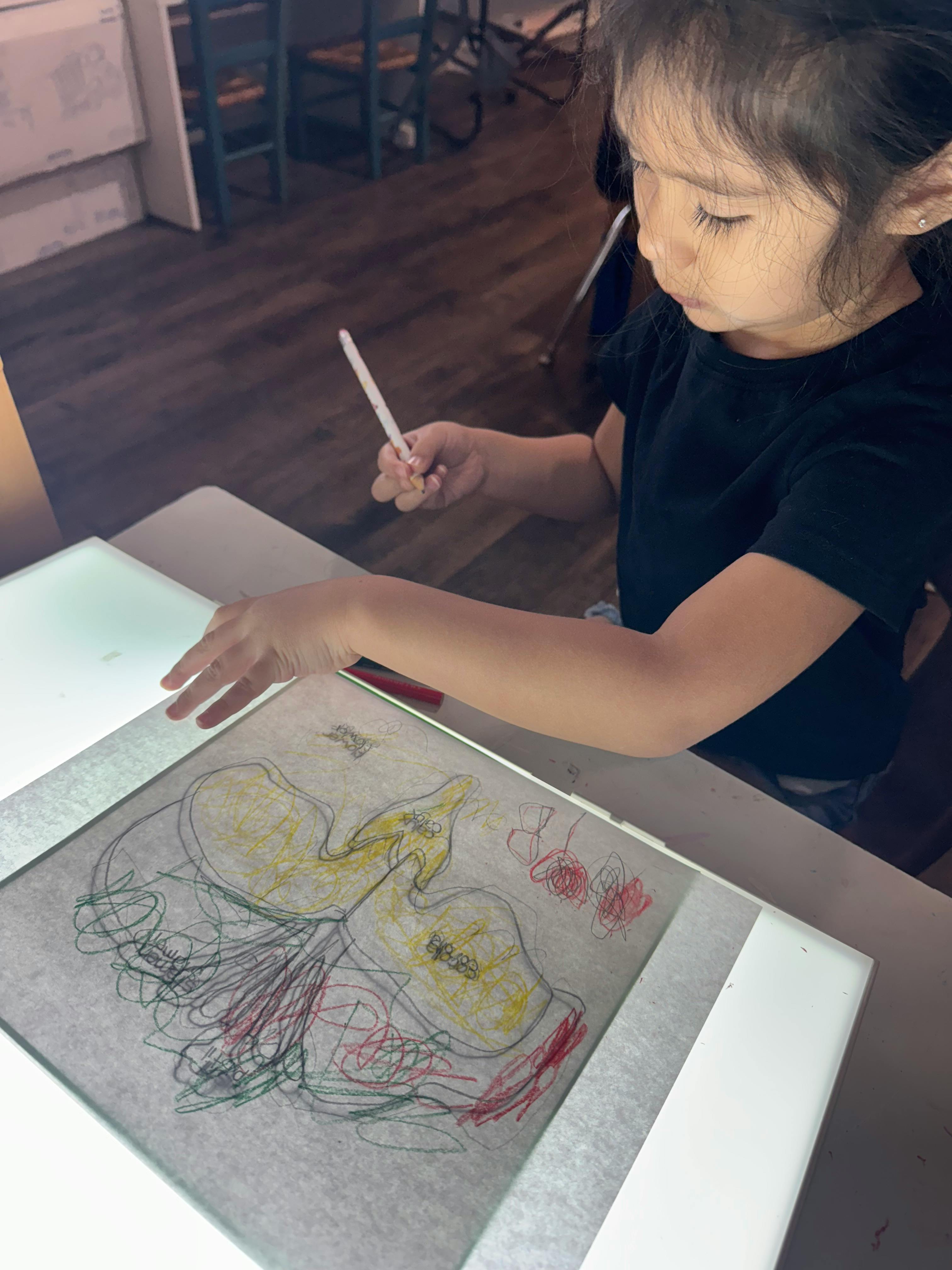 Child drawing on a light board