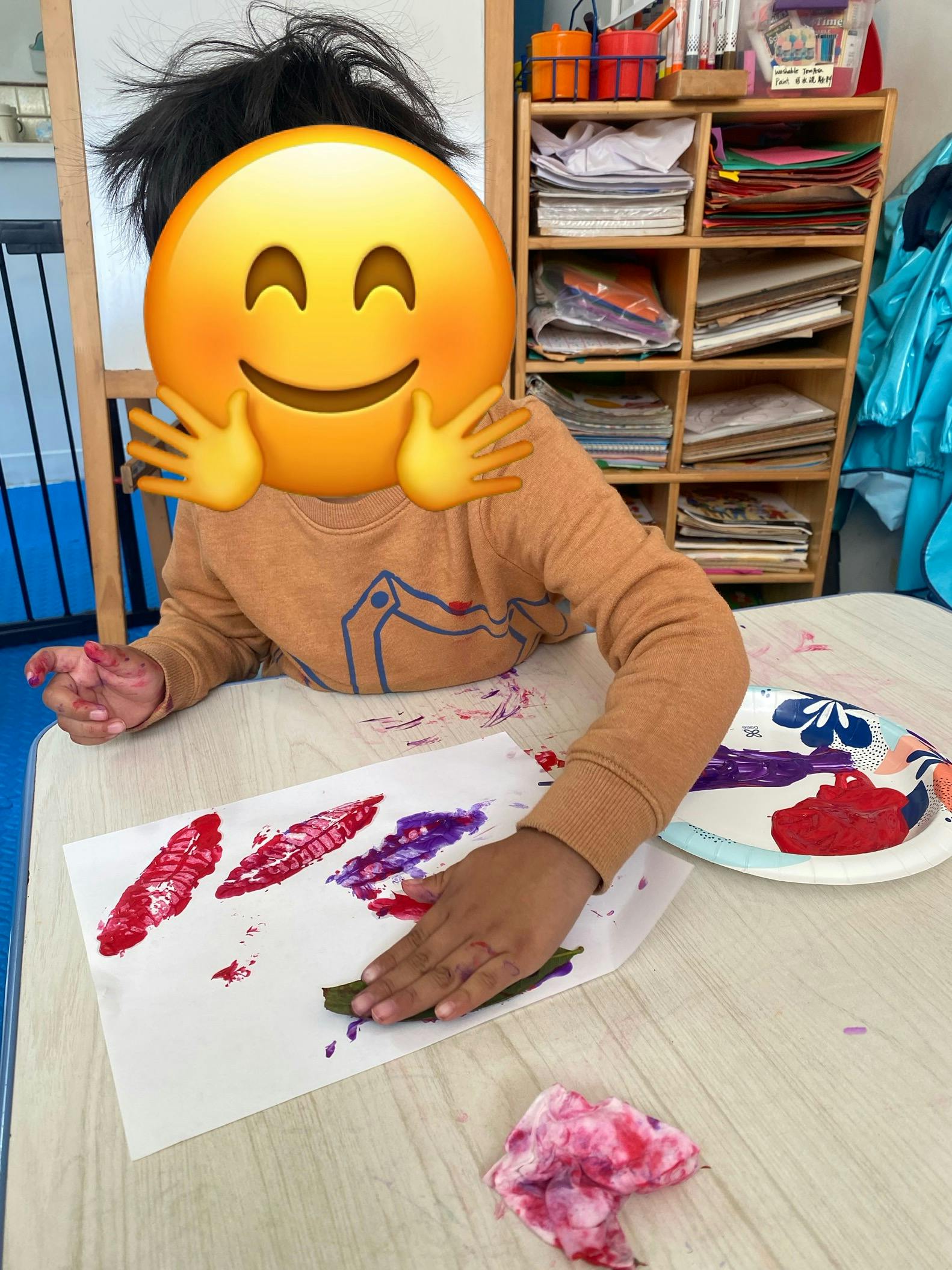 Child making art with paint and a leaf