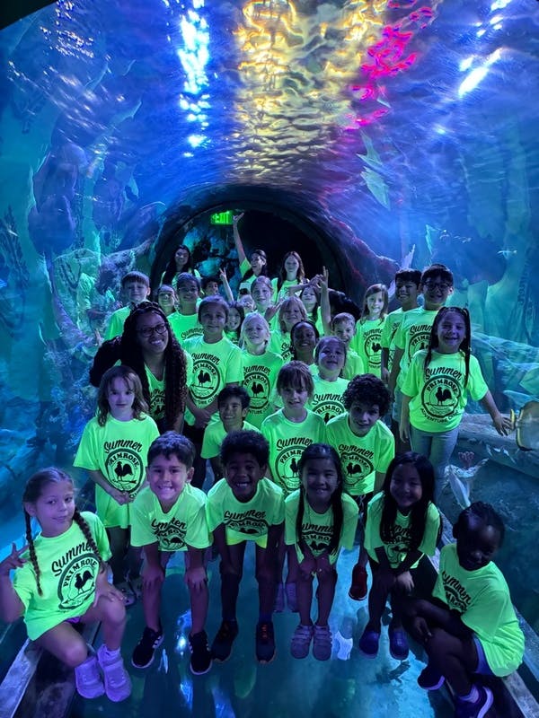 Group of children and adults in matching shirts in an underwater tunnel