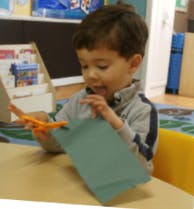 Child cutting paper with scissors