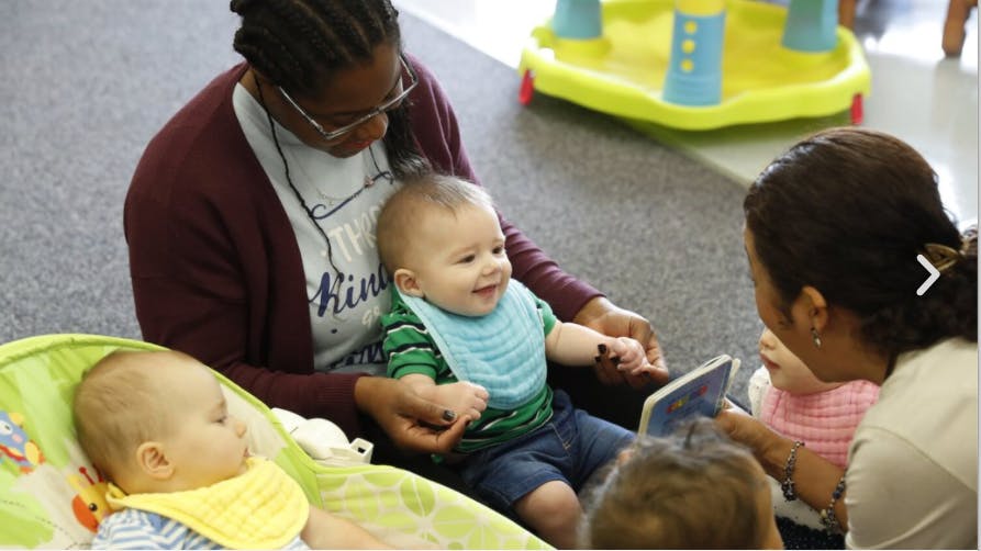 Two people with three babies in a classroom