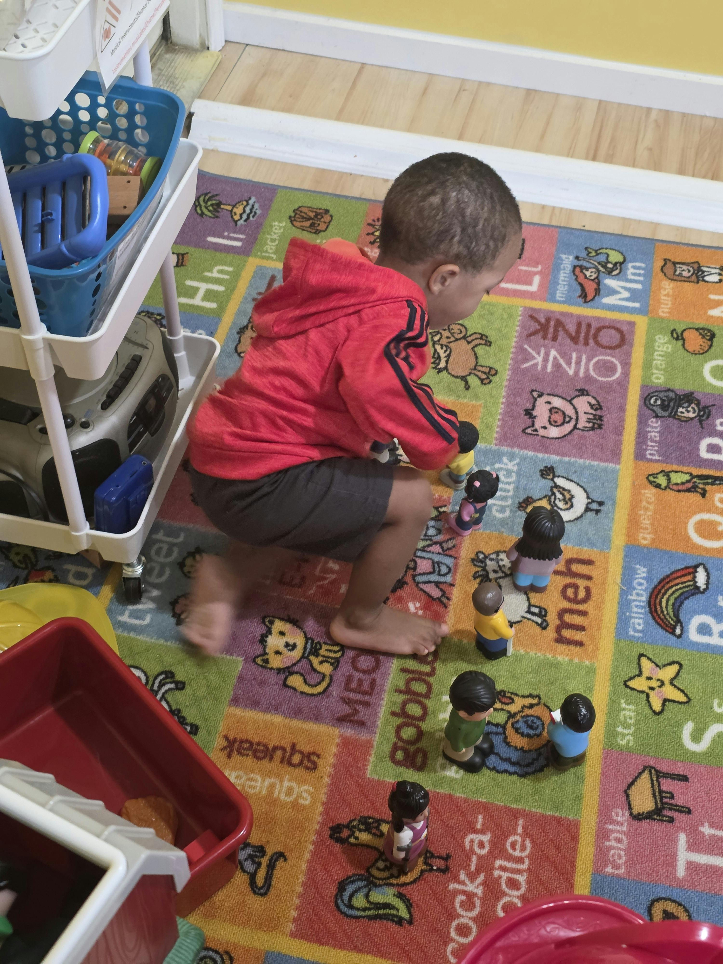 Child playing with toys on a colorful alphabet rug