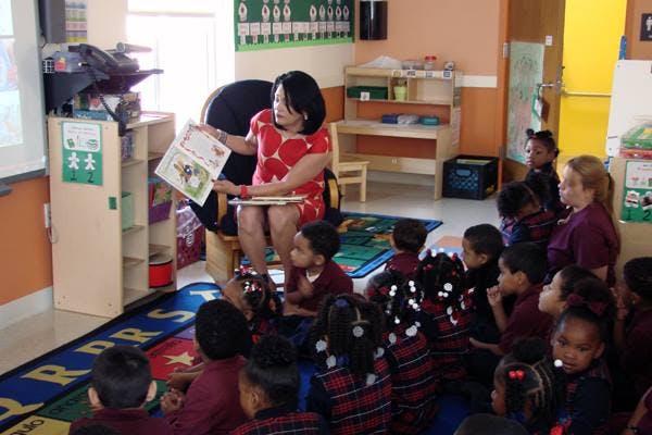 Person reading a book to a group of children in a classroom