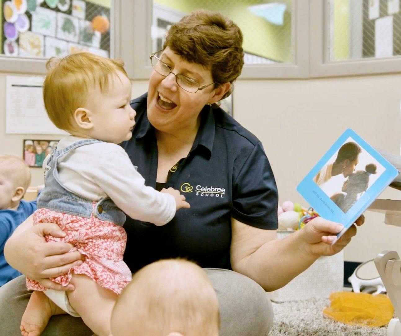 Person holding a child and a framed photo, looking at the child