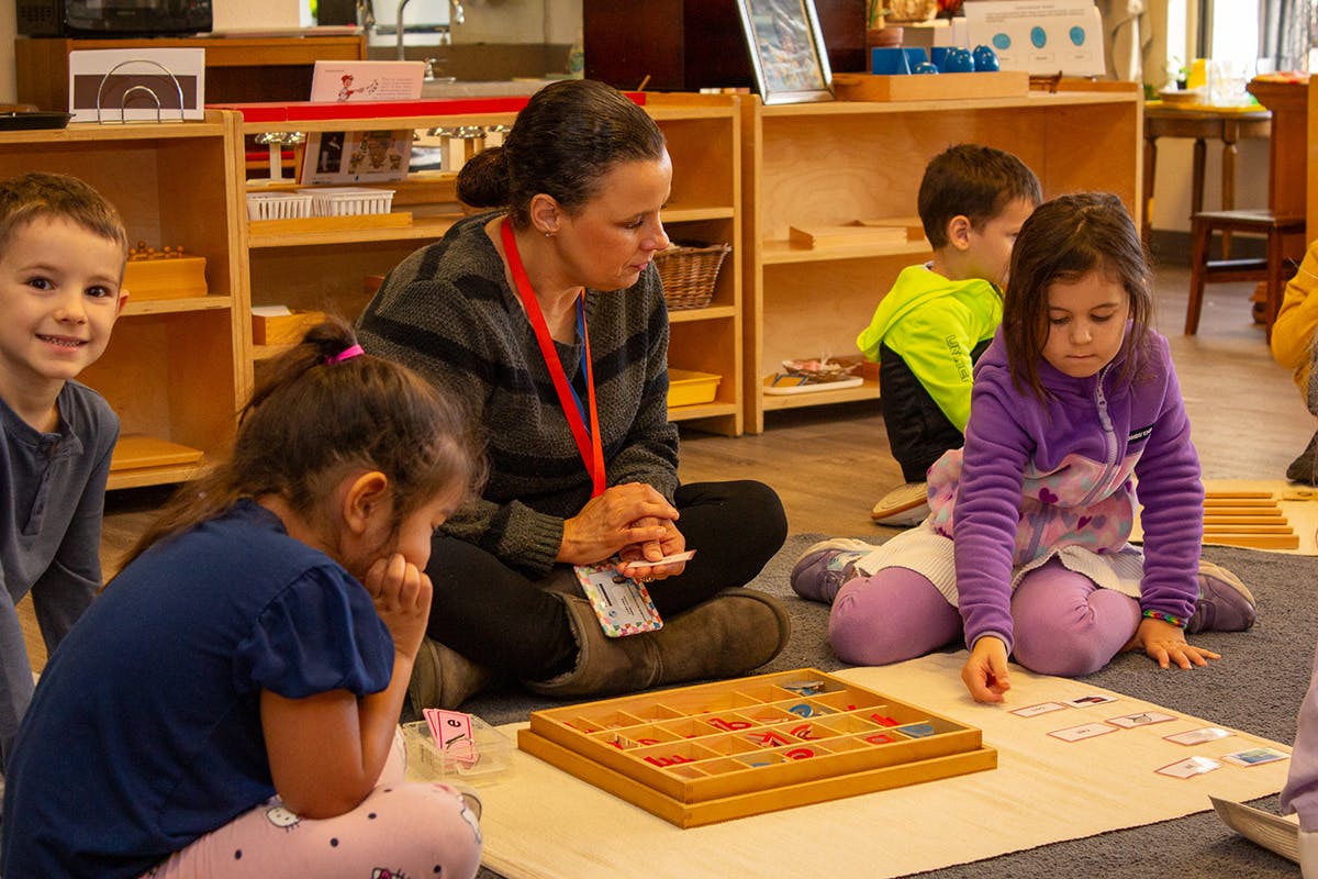 Adult and children sitting on floor with learning materials