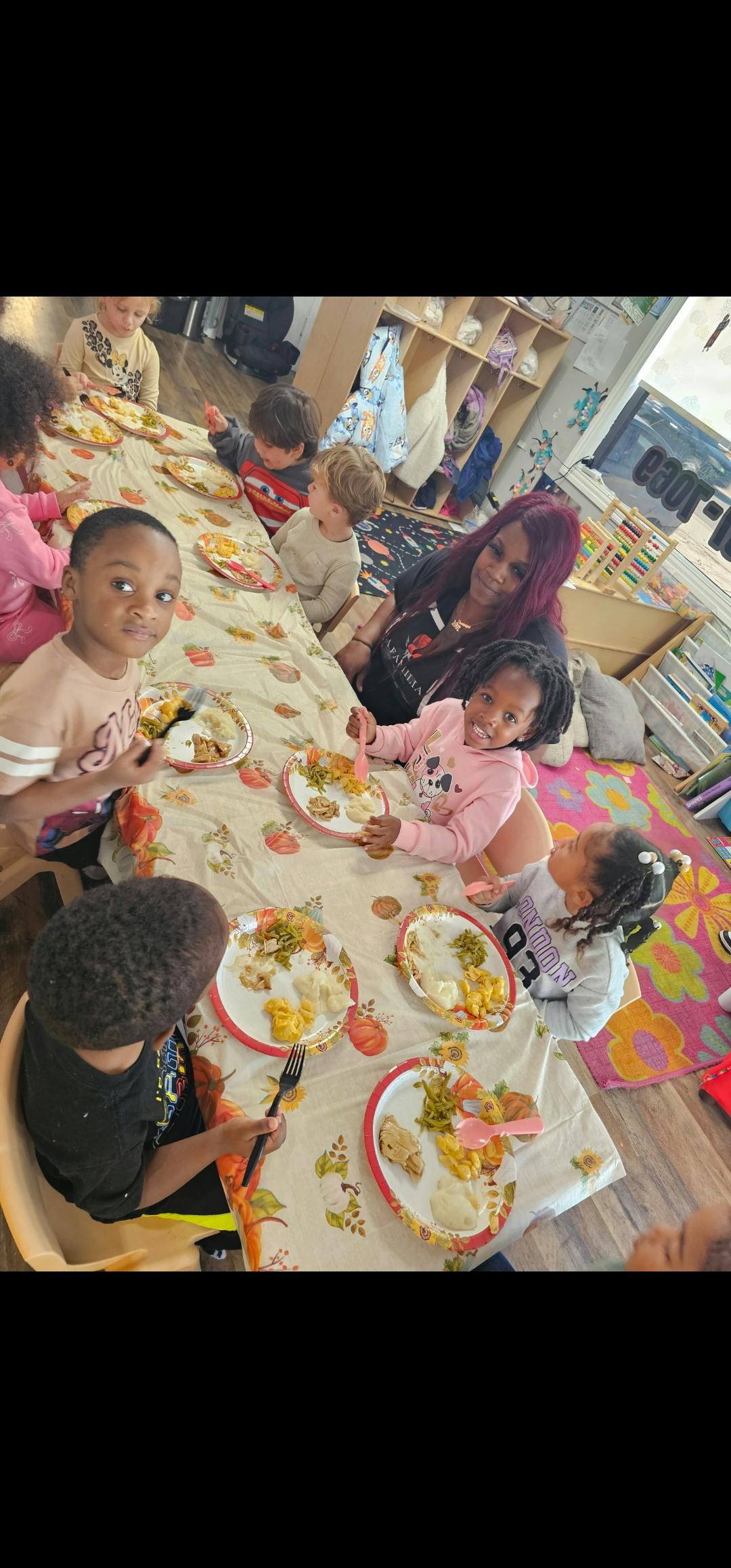 Children and a woman sitting around a table with plates of food