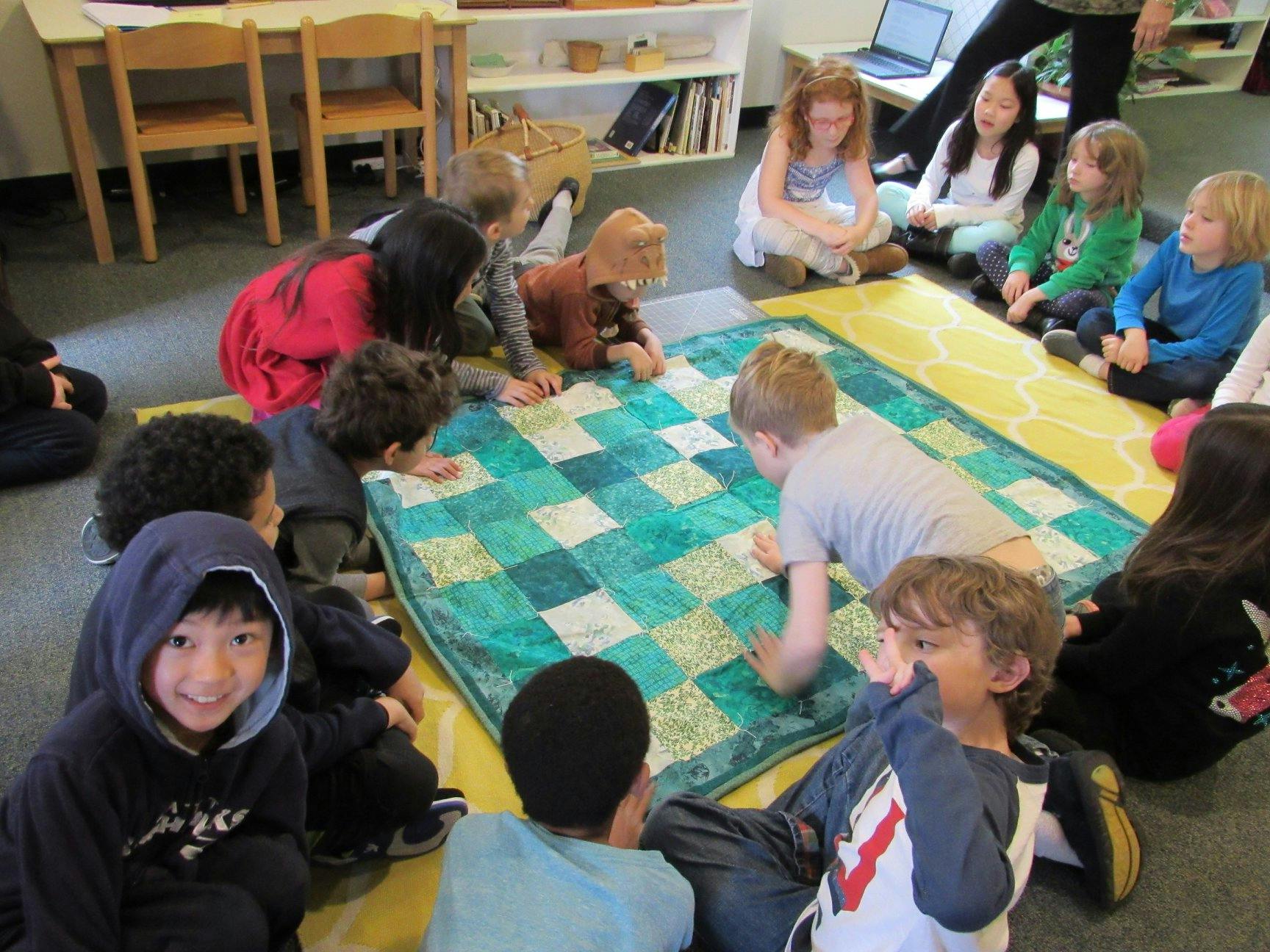 Children gathered around a patterned blanket on the floor