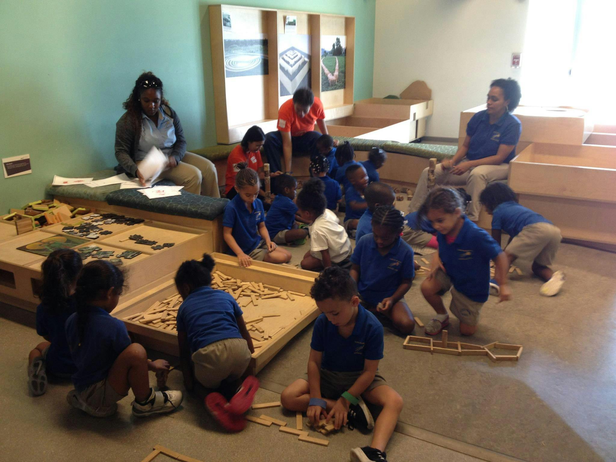 Adults and children in a classroom playing with wooden blocks
