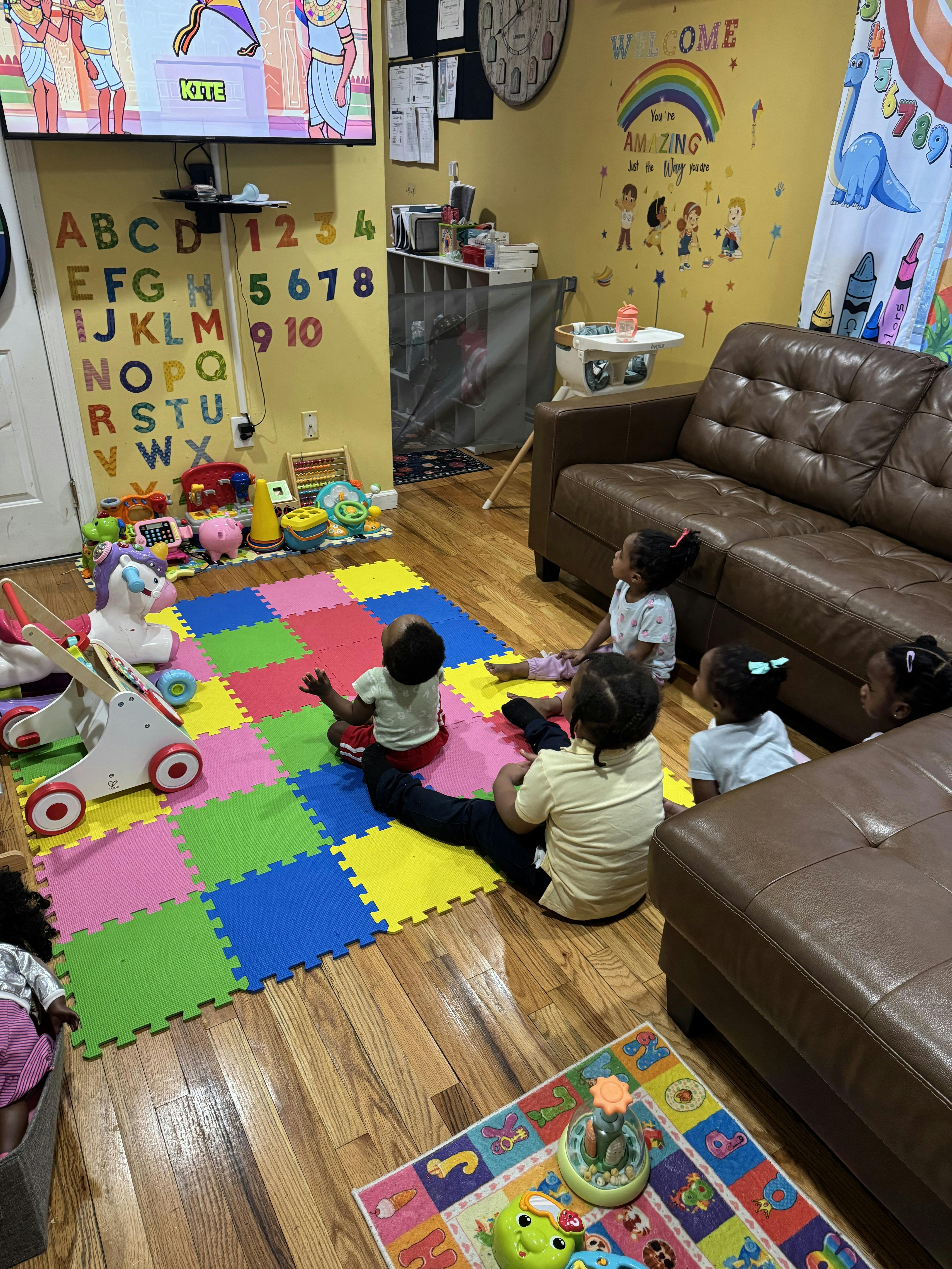 Children sitting on a colorful play mat watching television