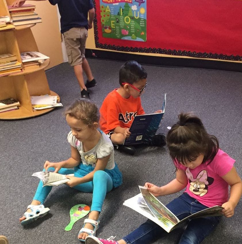 Three children sitting on the floor reading books
