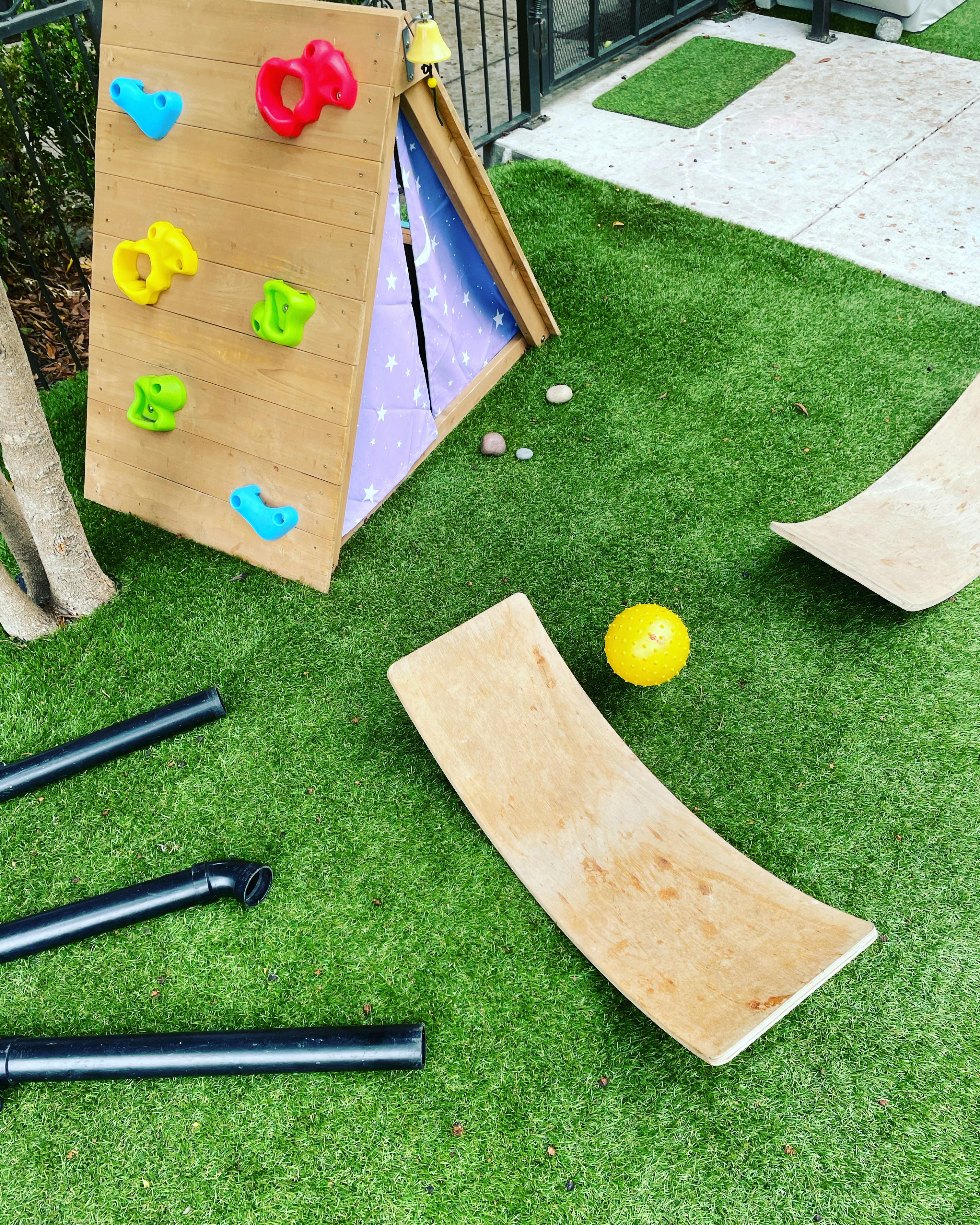 Climbing wall with colorful holds and wooden balance boards on artificial grass