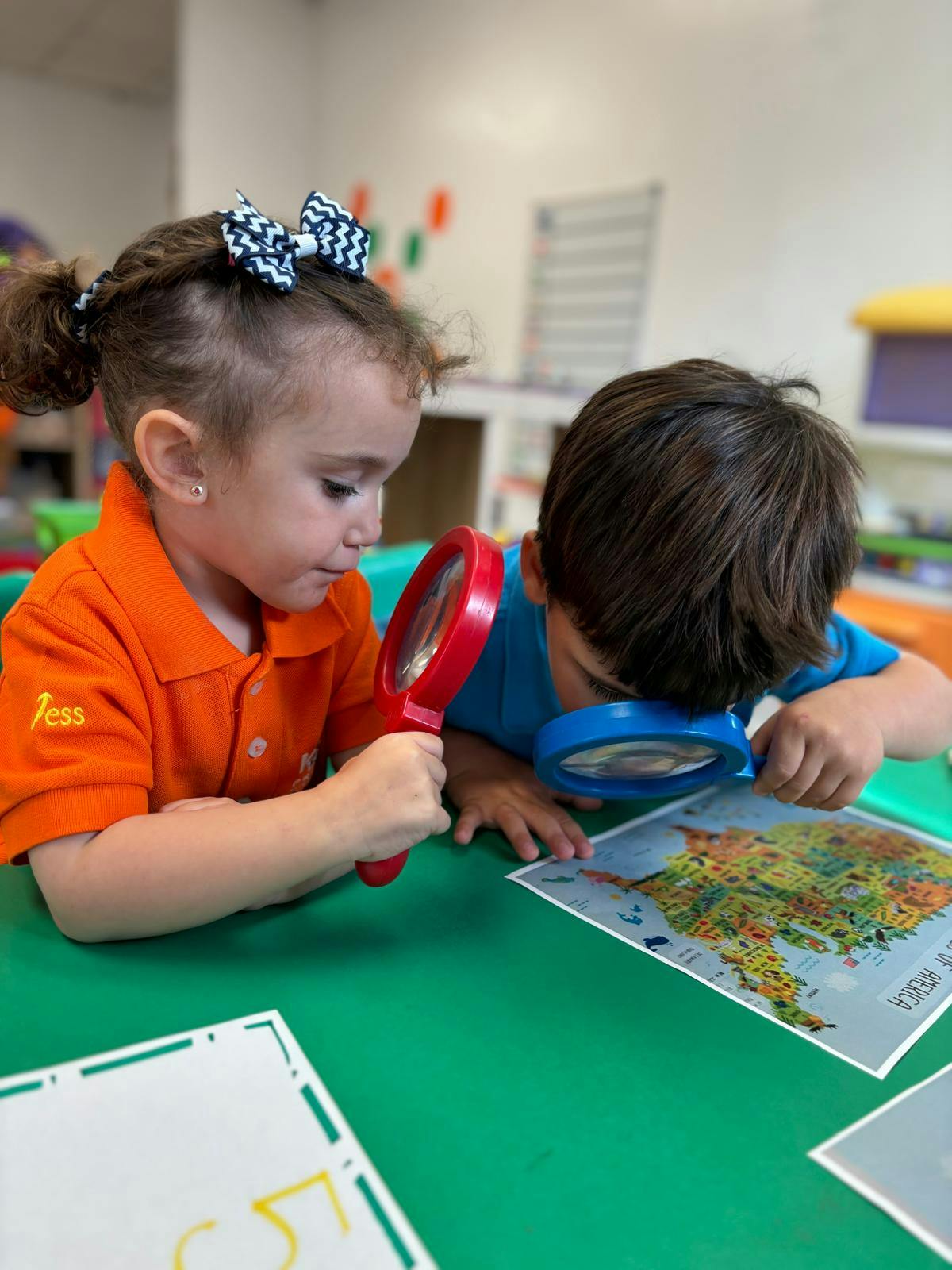 Two children looking at a map with magnifying glasses