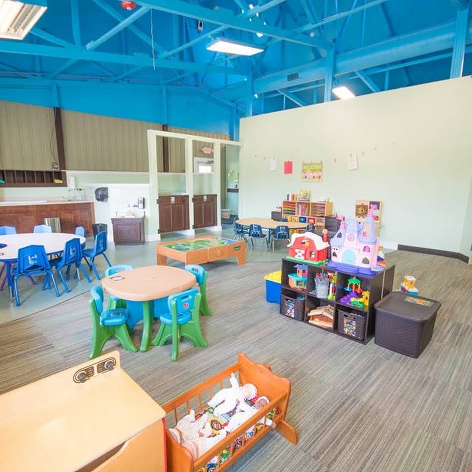 Playroom with small tables and chairs, toys, and a crib