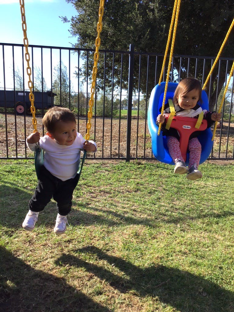Two children swinging on a playground