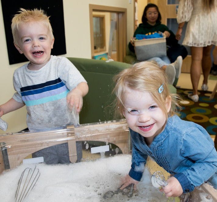 Two children playing in a tub of bubbles