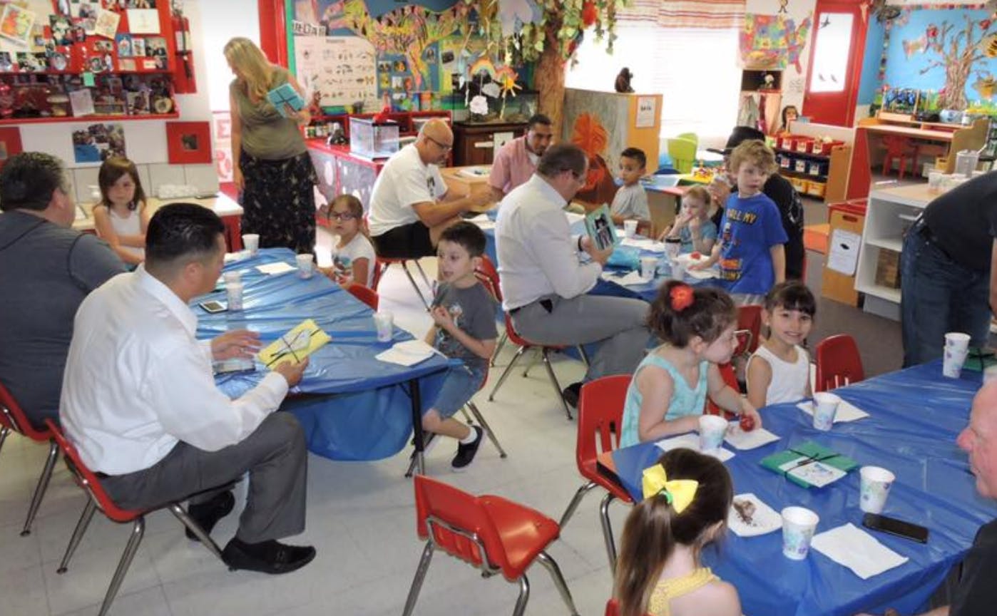 People and children sitting at tables in a classroom