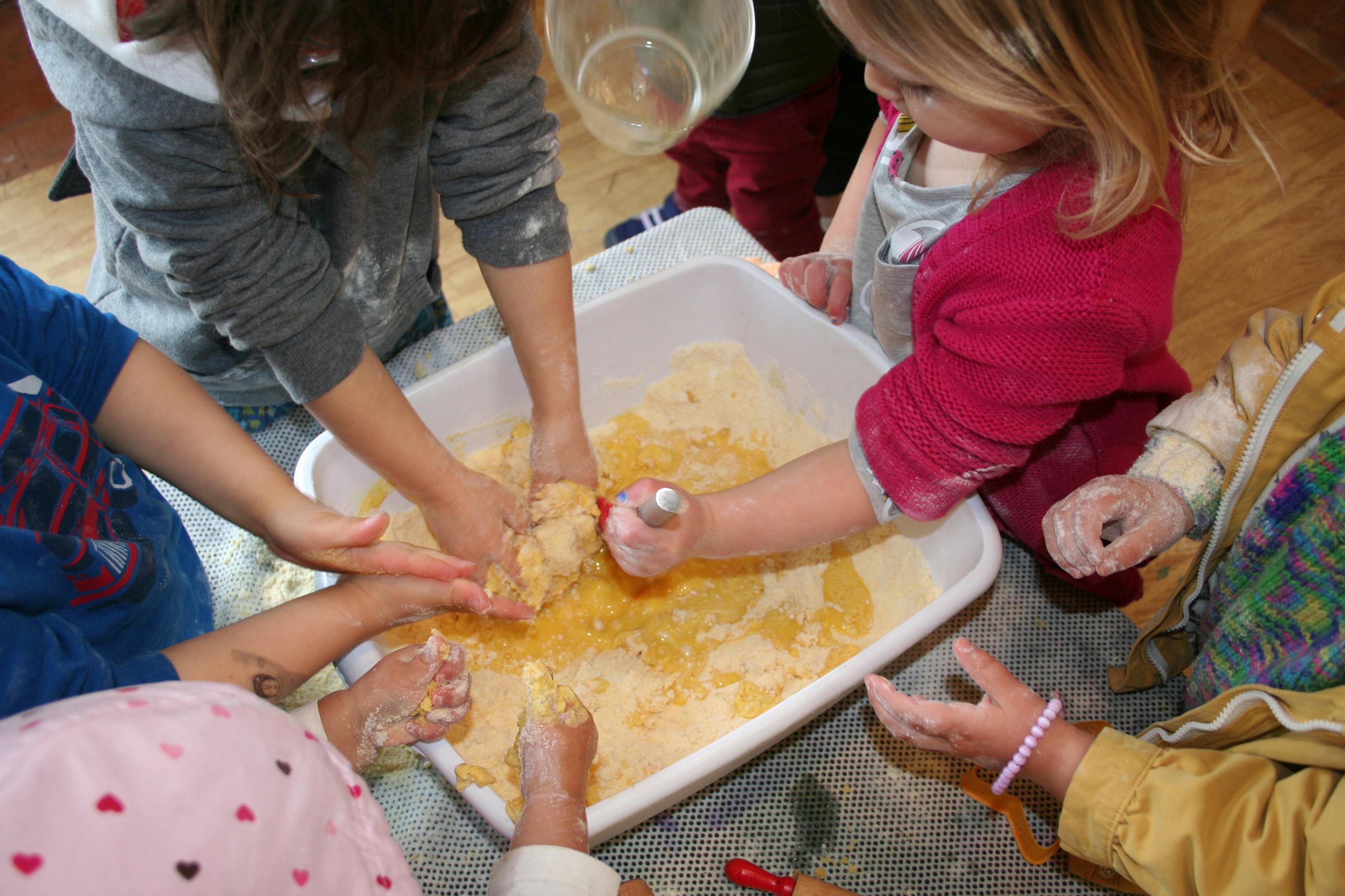 Children playing with a sensory bin filled with yellow and white material