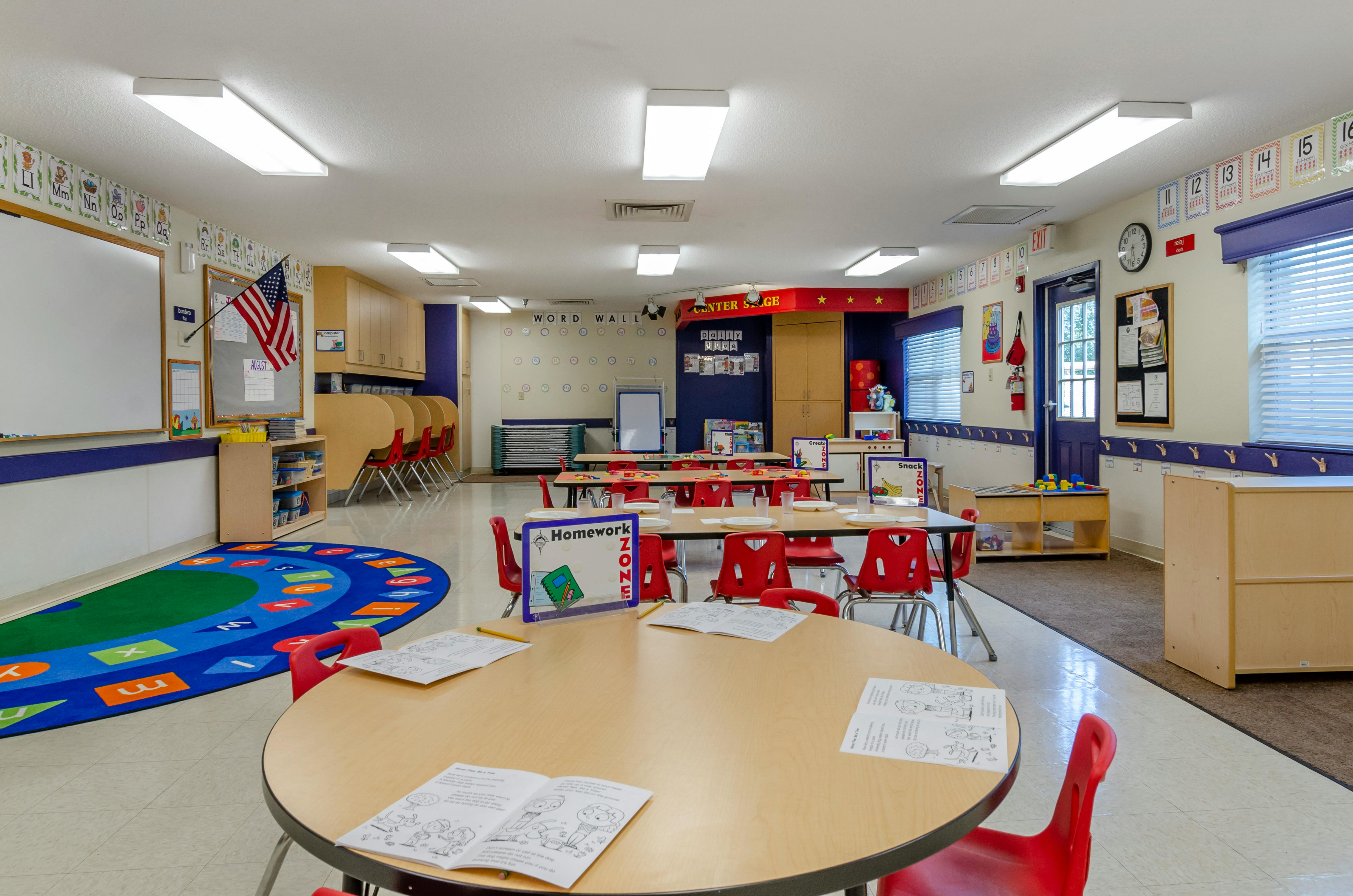 Classroom with tables, red chairs, and a colorful alphabet rug