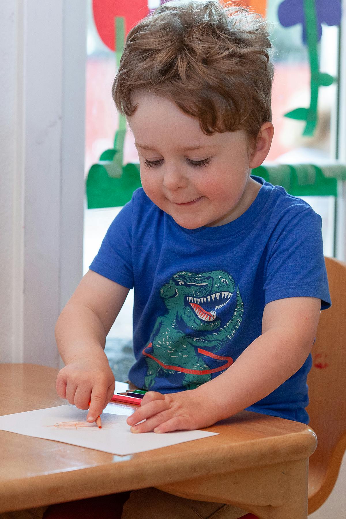 Child drawing on paper with a colored pencil
