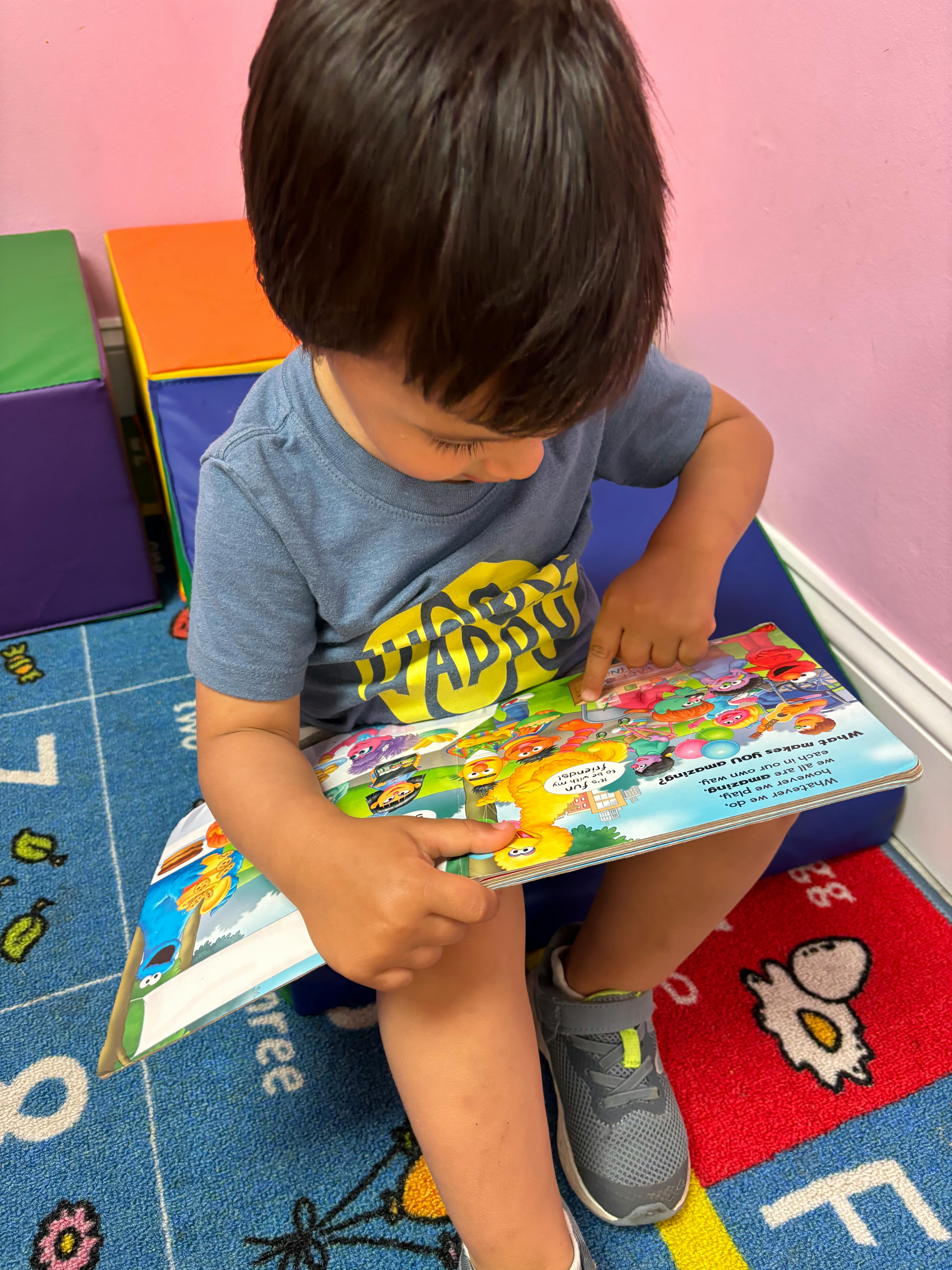 Child sitting and pointing at an open book