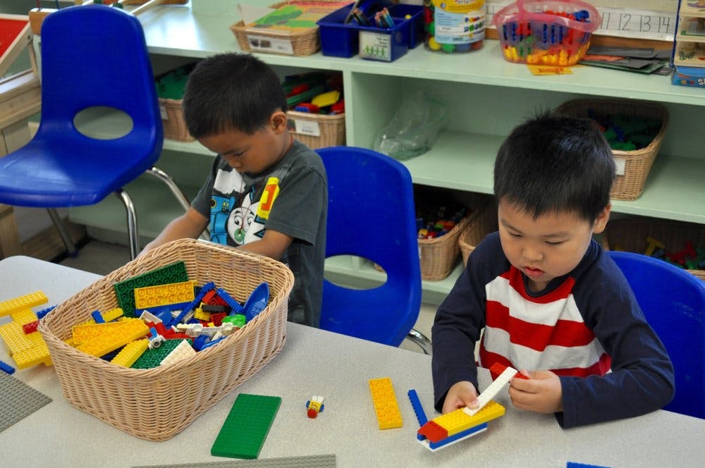 Two children playing with building blocks at a table