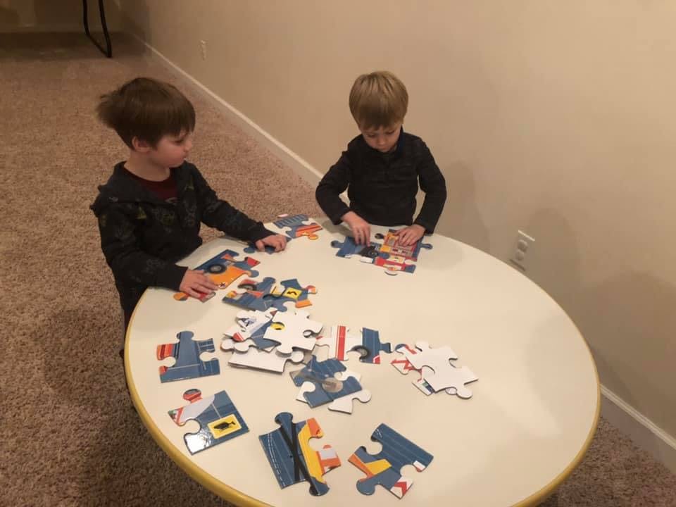 Two children assembling puzzles at a table
