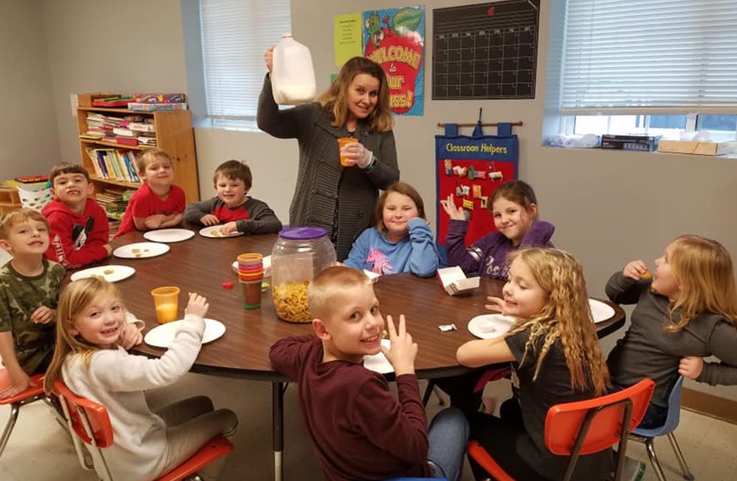 Adult and children sitting around a table with plates and cups