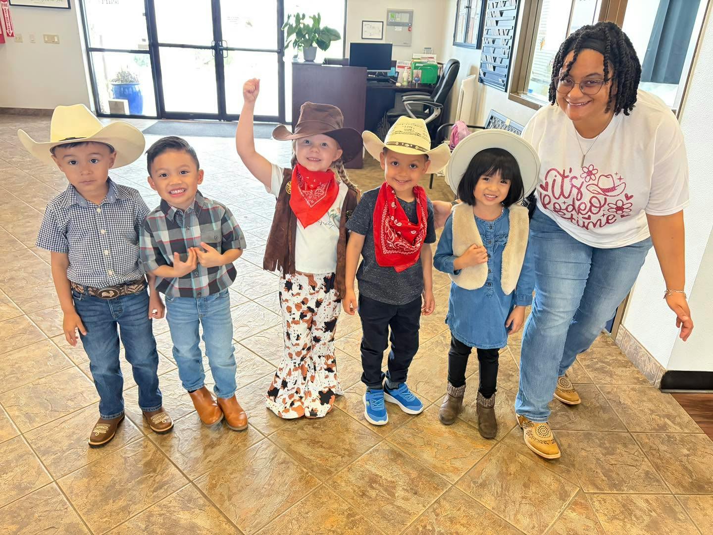 Five children and one adult dressed in cowboy attire, cowgirl, and rodeo attire
